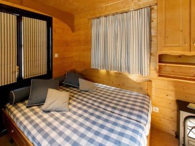Chalet en bois à Champagne-Ardennes, avec lit à baldaquin et rideaux rayés.