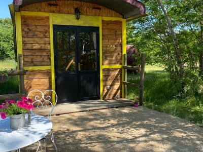 Charmante roulotte en bois avec une terrasse fleurie, située en pleine nature en Auvergne.