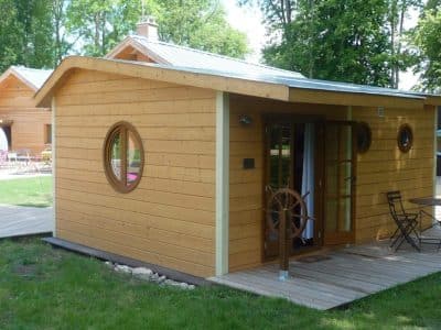 Cabane en bois avec un grand hublot et un baromètre, idéale pour un séjour insolite.