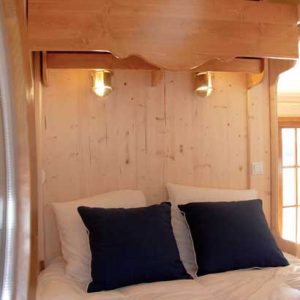 Chambre cosy en bois avec lit douillet et éclairage chaleureux à Champagne-Ardenne.
