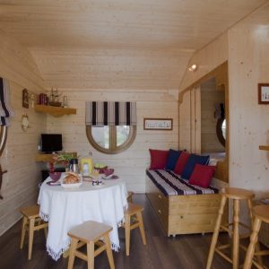 Hébergement insolite en Champagne-Ardenne : intérieur en bois avec table ronde et décor marin.