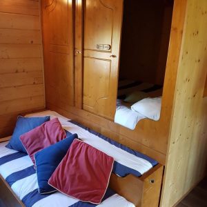 Chalet en bois à Champagne-Ardennes avec lits confortables et coussins colorés.