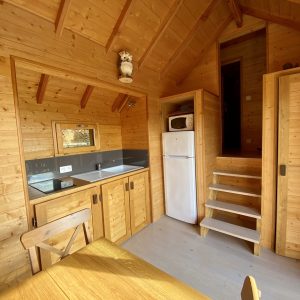 Cabane en bois chaleureuse avec cuisine équipée et escaliers en bois.