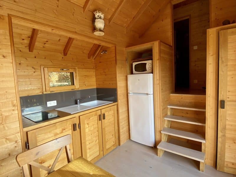 Chalet en bois chaleureux avec cuisine équipée et escaliers en bois.