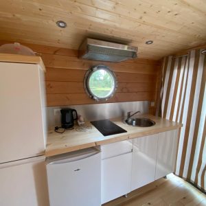 Cabane en bois à Auvergne, avec cuisine moderne et fenêtre ronde.