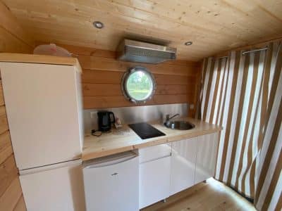 Cabane en bois à Auvergne, avec cuisine moderne et fenêtre ronde.
