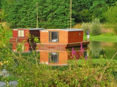Hébergement insolite : cabanes flottantes sur un lac, entourées de verdure.
