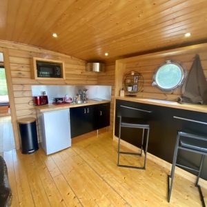 Hébergement insolite en Auvergne : intérieur en bois chaleureux avec cuisine équipée.