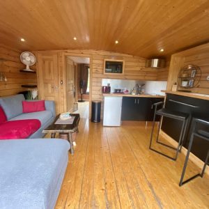 Hébergement insolite en Auvergne : intérieur en bois chaleureux avec canapé et kitchenette.