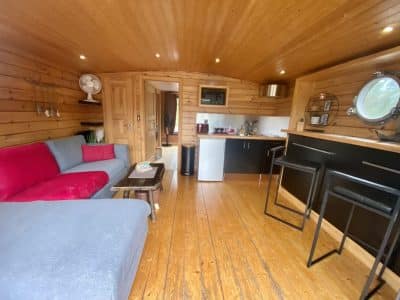 Hébergement insolite en Auvergne : intérieur en bois chaleureux avec canapé et kitchenette.