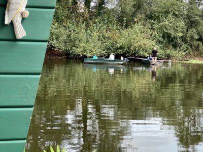 Cabane flottante en Auvergne, vue sur un homme en barque sur un lac paisible.