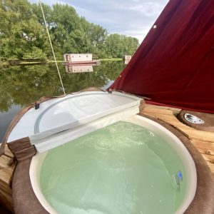 Hébergement insolite en Auvergne : un bateau avec jacuzzi sur leau paisible.