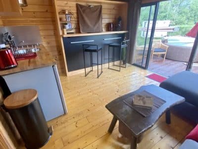 Hébergement insolite en Auvergne : chalet en bois avec cuisine ouverte et vue sur la nature.