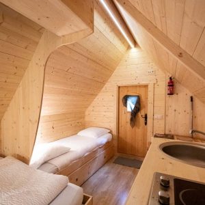 Cabane en bois à Champagne-Ardennes, intérieur cosy avec lit simple et kitchenette.