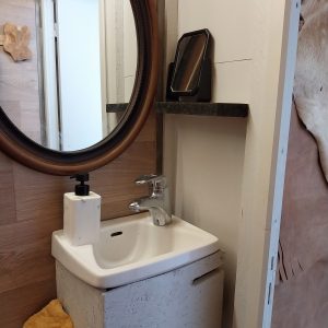 Salle de bain dun hébergement insolite en Aquitaine avec miroir rond et lavabo moderne.
