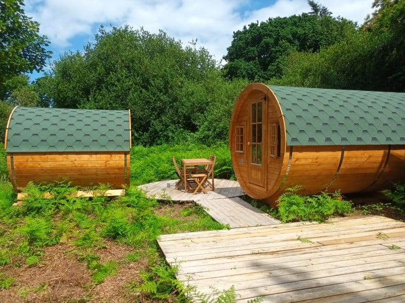 Hébergement insolite en Bretagne : cabanes en bois avec toit vert, entourées de verdure.