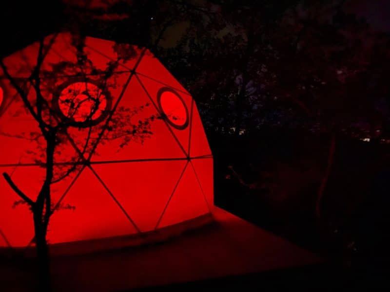 Dôme géodésique illuminé en rouge, niché dans la nature du Languedoc-Roussillon.