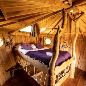 Chalet en bois en Bretagne avec un lit en rondins et un intérieur chaleureux.