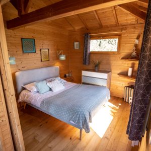 Chalet en bois lumineux en Bretagne, avec un lit douillet et des murs en bois chaleureux.