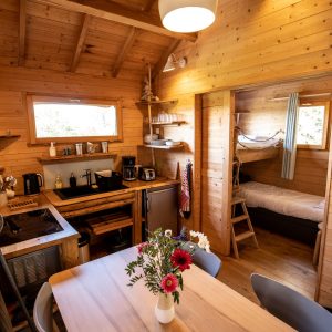 Cabane en bois en Bretagne, intérieur chaleureux avec table en bois et fleurs.