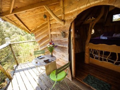 Cabane perchée en Bretagne avec terrasse en bois et vue sur la nature environnante.