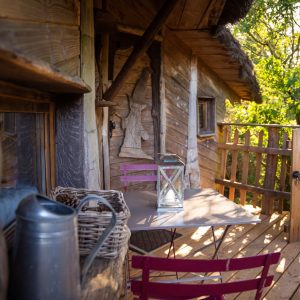 Cabane en bois en Bretagne avec une terrasse ensoleillée et des chaises colorées.