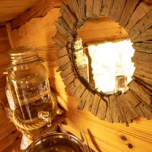 Cabane en bois en Bretagne avec miroir rustique et jarre en verre.