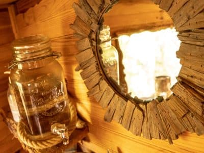 Cabane en bois en Bretagne avec miroir rustique et jarre en verre.