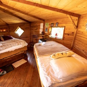Chalet en bois chaleureux en Bretagne, avec lits douillets et fenêtres en forme de losange.