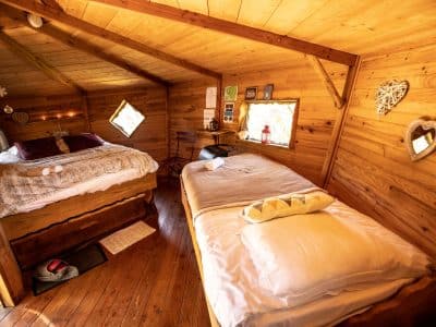 Chalet en bois chaleureux en Bretagne, avec lits douillets et fenêtres en forme de losange.