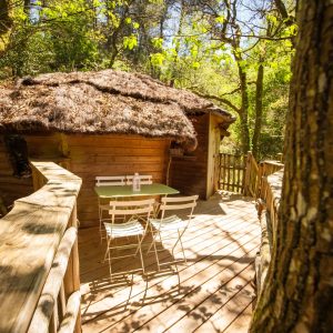 Cabane perchée en Bretagne, avec terrasse en bois et mobilier blanc.