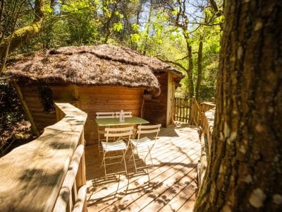 Cabane perchée en Bretagne, avec terrasse en bois et mobilier blanc.