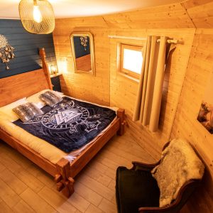 Chalet en bois cosy en Bretagne, lit douillet avec décor chaleureux et touches naturelles.