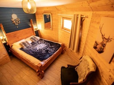 Chalet en bois cosy en Bretagne, lit douillet avec décor chaleureux et touches naturelles.