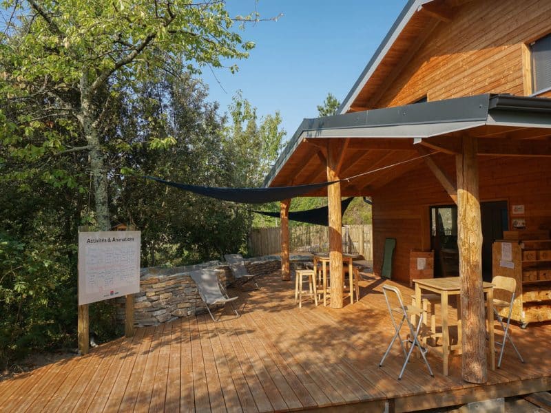Chalet en bois avec terrasse ensoleillée et mobilier extérieur accueillant.