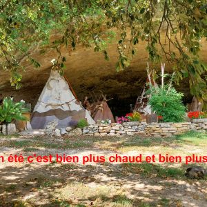 Tipis colorés sous une grande roche, entourés de verdure et de fleurs en Aquitaine.