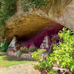 Tipis sous une roche, entourés de verdure et de fleurs colorées en Aquitaine.