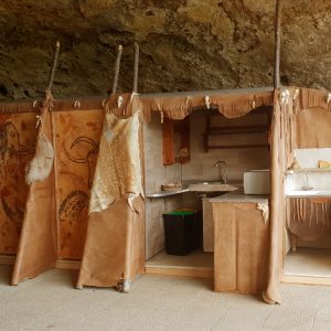 Hébergement insolite en Aquitaine : cabane en toile sous une roche, décor naturel.