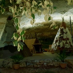 Tentes tipi sous une grotte en Aquitaine, entourées de verdure et de lumière douce.