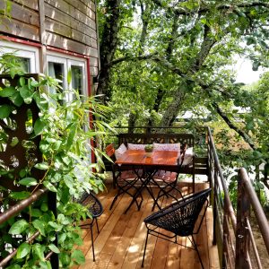 Cabane perchée en Languedoc-Roussillon avec terrasse en bois entourée de verdure.
