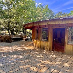 Cabane en bois avec terrasse spacieuse, entourée de verdure à Languedoc-Roussillon.