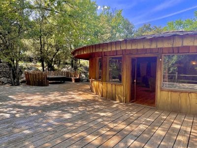 Cabane en bois avec terrasse spacieuse, entourée de verdure à Languedoc-Roussillon.