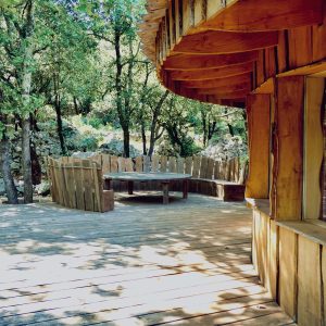 Cabane en bois dans les arbres, avec une terrasse en bois et un coin repas.