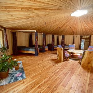 Yourte spacieuse en bois, avec un intérieur chaleureux et des lits confortables.