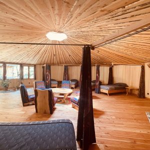 Yourte spacieuse en bois, avec un intérieur chaleureux et lumineux, idéal pour un séjour unique.