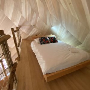 Chalet en bois en Bretagne, avec un lit douillet et des murs en bois clair.