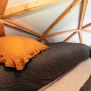 Dôme géodésique en Auvergne-Rhône-Alpes, avec literie cosy et murs en bois.