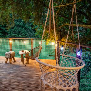 Cabane perchée en Auvergne-Rhône-Alpes, avec un hamac suspendu et éclairage chaleureux.