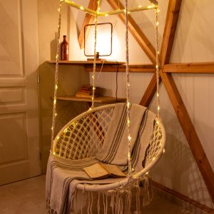 Hébergement insolite en Auvergne-Rhône-Alpes avec un fauteuil suspendu décoré de guirlandes