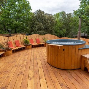 Hébergement insolite en Languedoc-Roussillon avec jacuzzi en bois et chaises confortables.